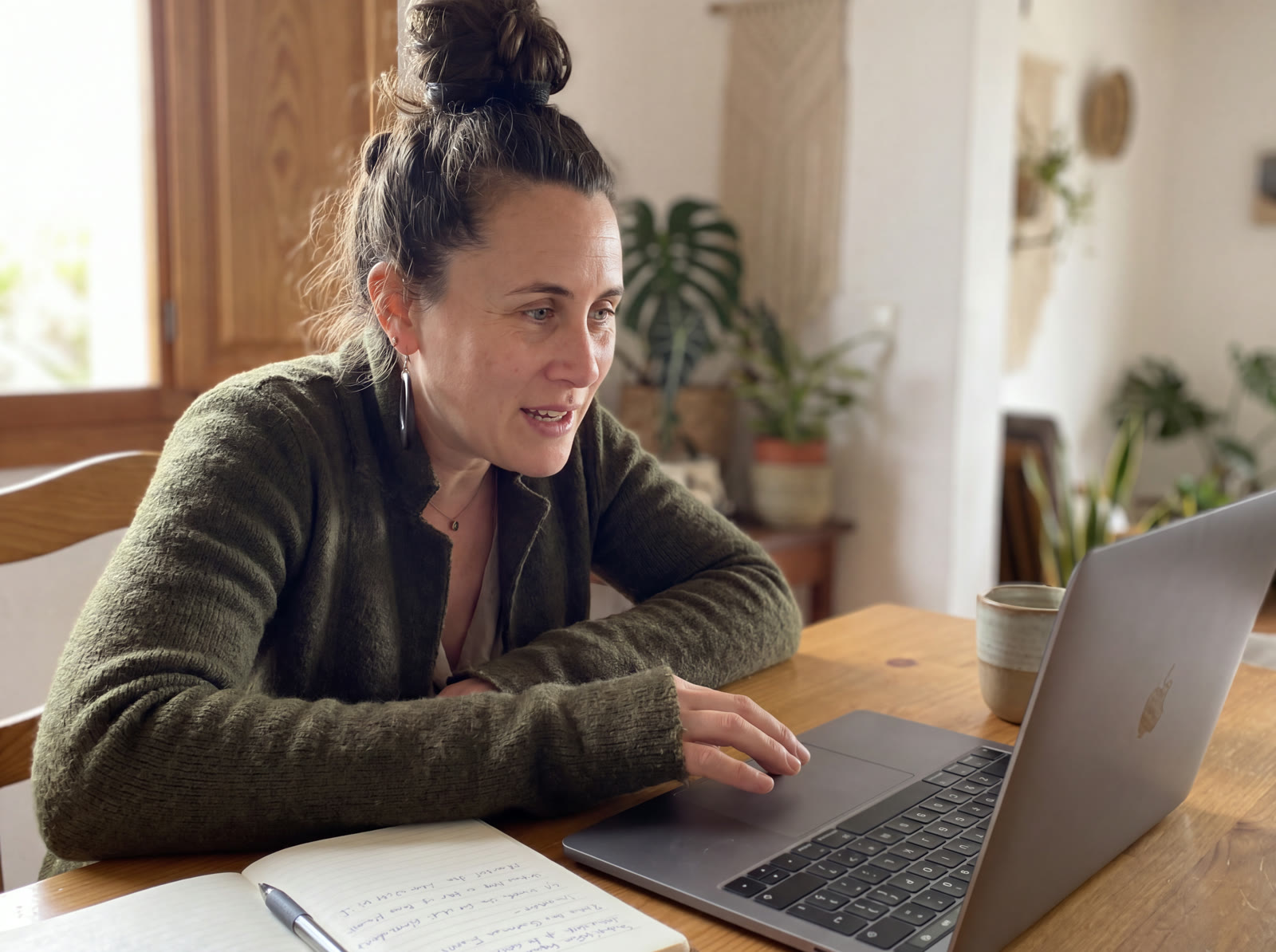 Stefanie Fischer arbeitet am Laptop im warmen Licht ihres Zuhauses, daneben ein Notizbuch